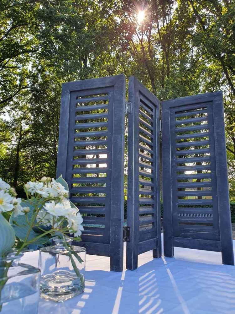 Raamshutter zwart 52 cm Black Berlin buiten in tegenlicht met bloemen